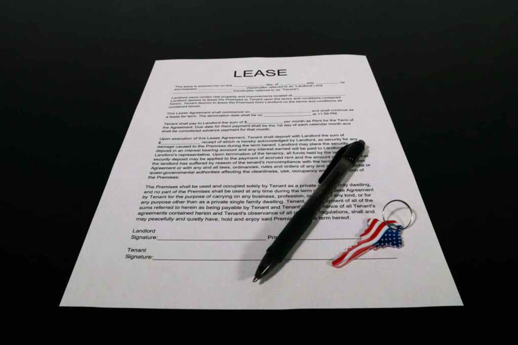 Lease agreement document with pen and American flag keychain on a black table.