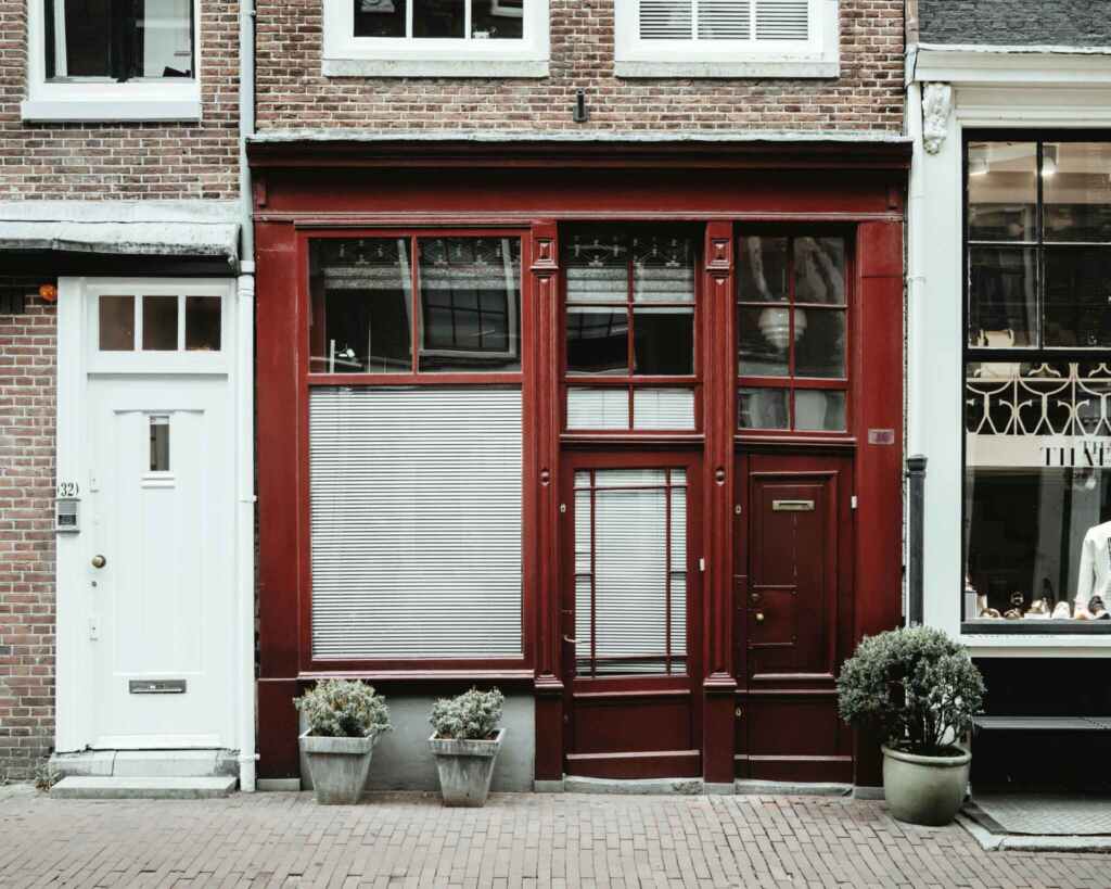 A charming red brick facade with potted plants on a quiet urban street.