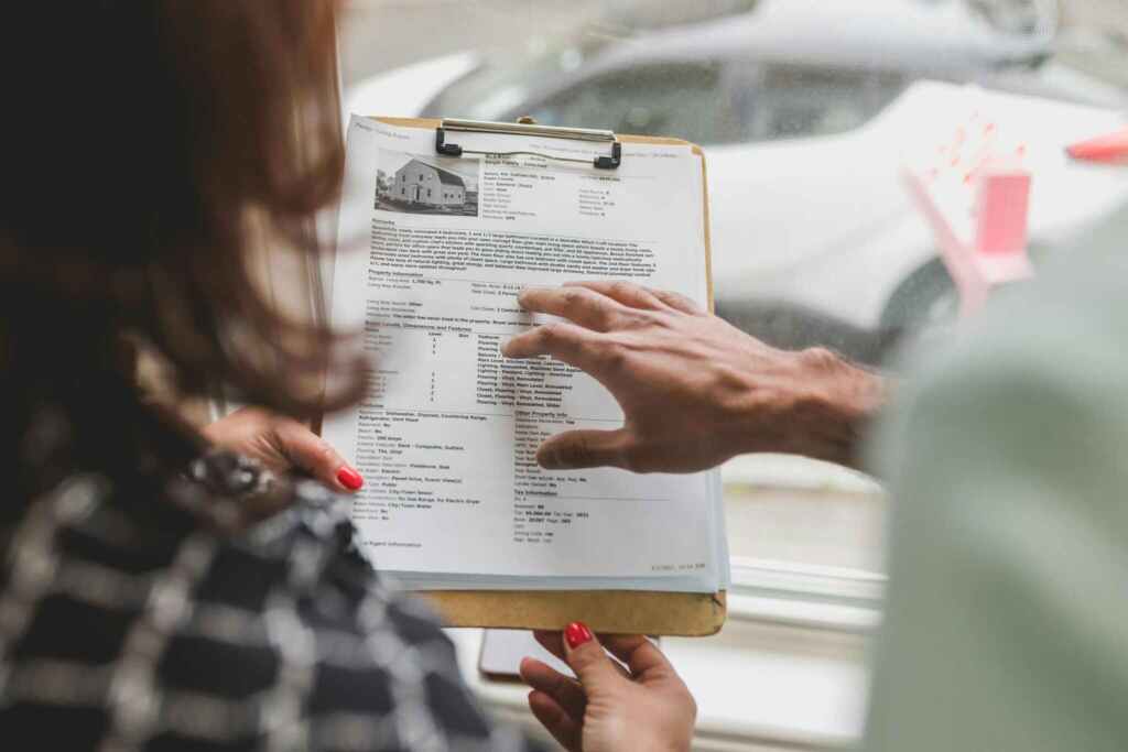 Real estate agent discussing property details with client using a clipboard indoors.
